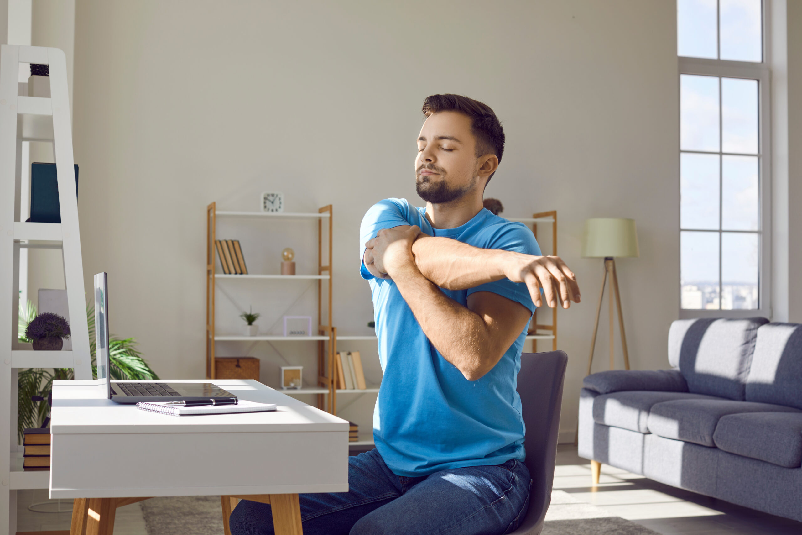 remote worker taking a moment to stretch his shoulders and upper body to help stay healthy during the day